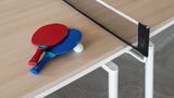 Miza za Namizni tenis z modrim in rdečim loparjem ter žogico na lesenem površju.
