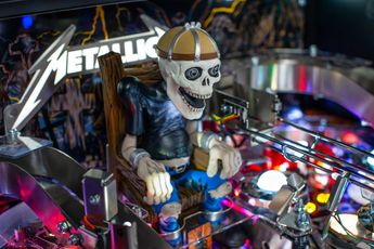 Fliper Stern Metallica Remastered: skeleton figure on pinball machine with vibrant lights and Metallica logo